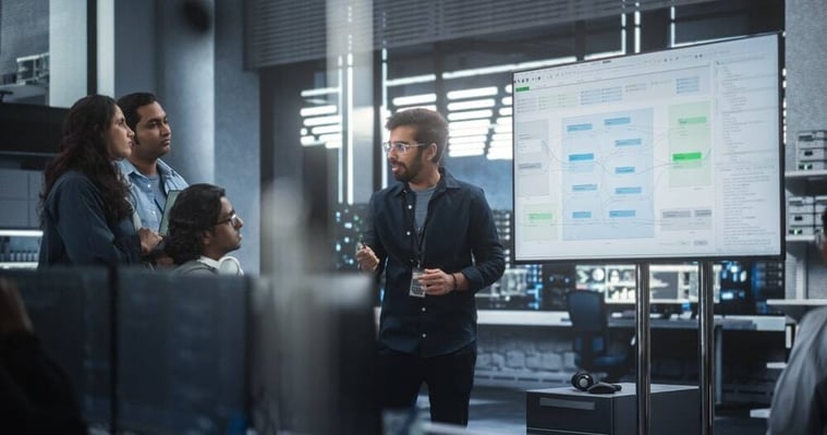 Team discussing a business strategy diagram on a large screen during a meeting.